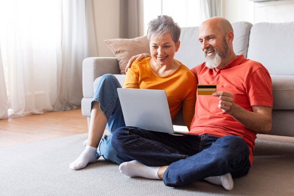 man and woman sitting on floor with laptop and credit card in hand