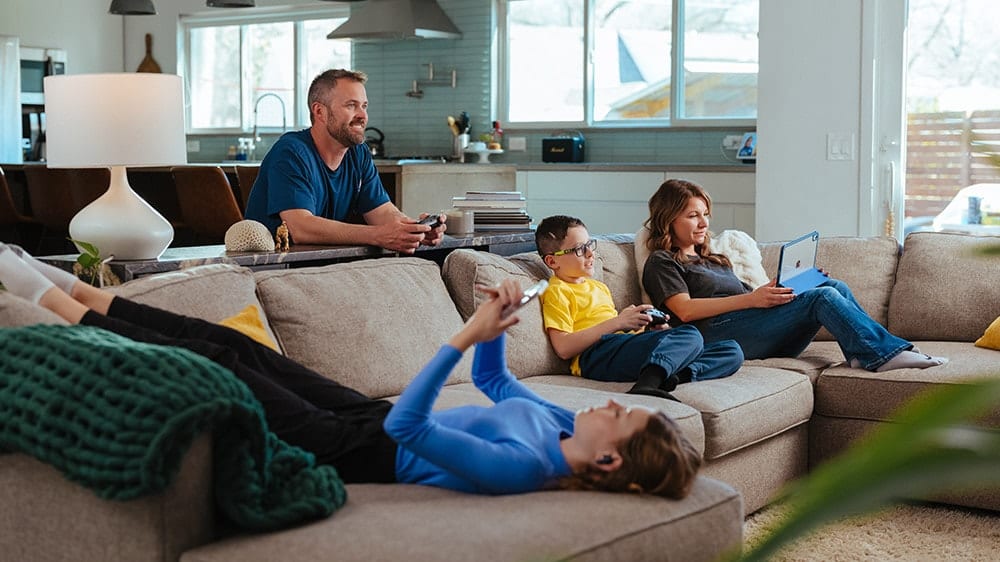 family sitting on couch playing games together enjoying fast home internet from Mercury
